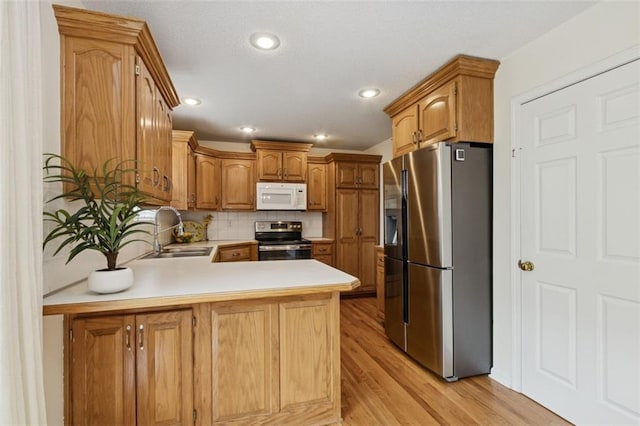 15050 W 145th St, Olathe, KS 66062 - kitchen with stainless steel appliances, a sink, a peninsula, light countertops, and light wood-type flooring