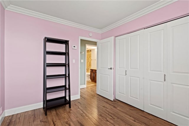 700 E 8th St Unit 11T, Kansas City, MO 64106 - unfurnished bedroom with crown molding, baseboards, hardwood / wood-style flooring, and a closet