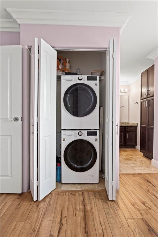 700 E 8th St Unit 11T, Kansas City, MO 64106 - laundry room featuring stacked washing machine and dryer, crown molding, and light wood-style floors