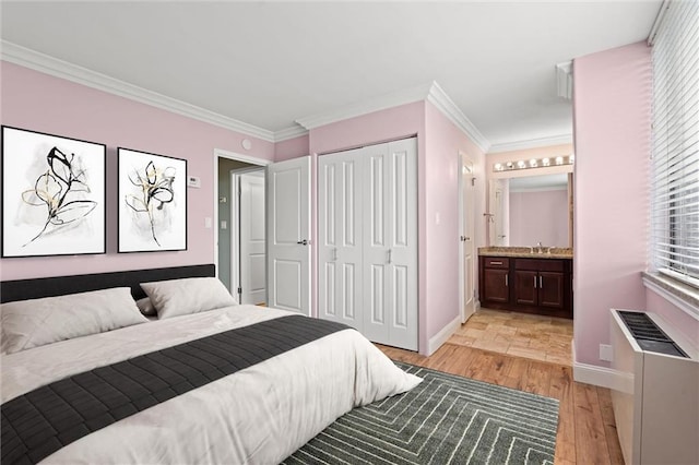 700 E 8th St Unit 11T, Kansas City, MO 64106 - bedroom with light wood-style floors, baseboards, a sink, crown molding, and connected bathroom