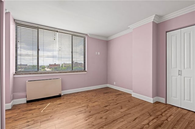 700 E 8th St Unit 11T, Kansas City, MO 64106 - unfurnished bedroom featuring light wood-style flooring, baseboards, crown molding, and a closet