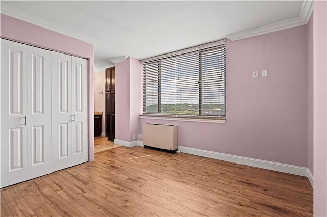700 E 8th St Unit 11T, Kansas City, MO 64106 - unfurnished bedroom featuring ornamental molding, baseboards, a closet, and light wood-style floors