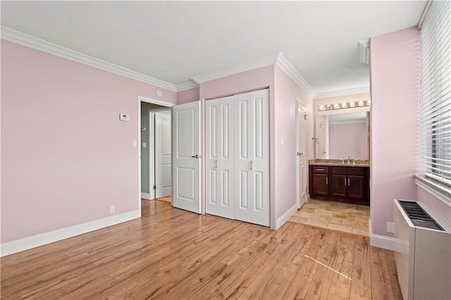 700 E 8th St Unit 11T, Kansas City, MO 64106 - unfurnished bedroom with light wood finished floors, baseboards, a sink, ornamental molding, and connected bathroom