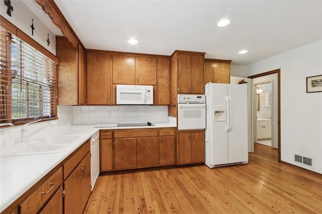 5407 W 64th Ter, Prairie Village, KS 66208 - kitchen featuring white appliances, brown cabinetry, a sink, light wood finished floors, and tasteful backsplash