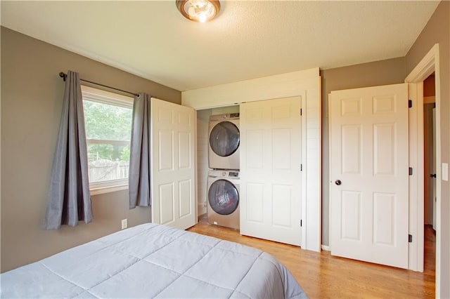 7610 NE Bacon Rd, Cameron, MO 64429 - bedroom featuring stacked washing machine and dryer, light wood-style flooring, and a closet