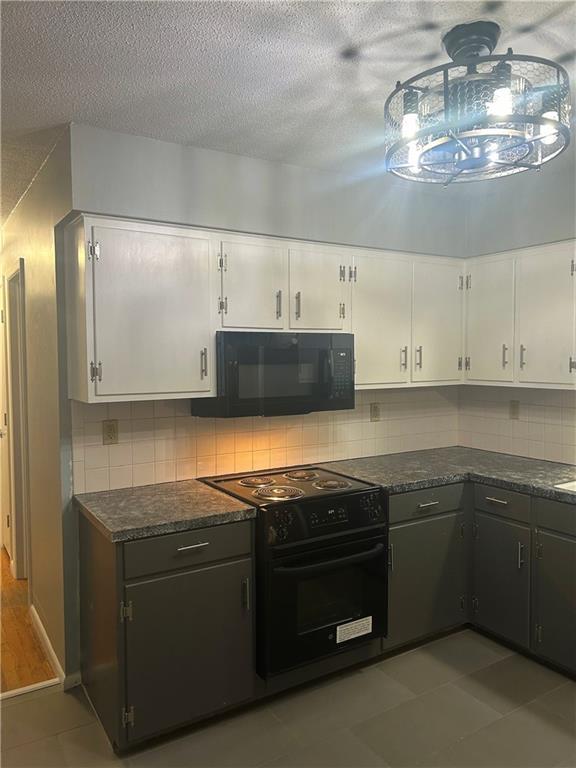1923 Seneca St, Leavenworth, KS 66048 - kitchen with black appliances, white cabinets, dark countertops, a textured ceiling, and tasteful backsplash