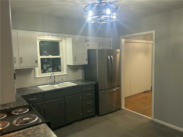 1923 Seneca St, Leavenworth, KS 66048 - kitchen with freestanding refrigerator, dark countertops, white cabinetry, decorative backsplash, and a textured ceiling