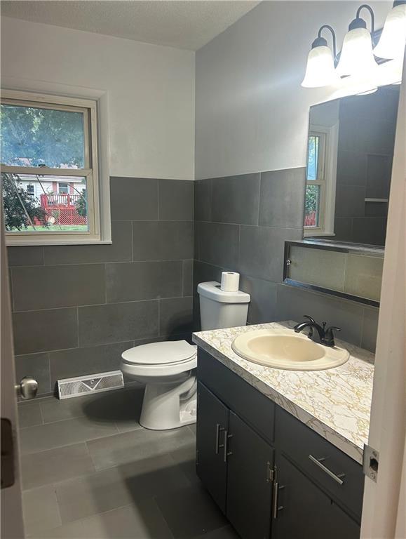 1923 Seneca St, Leavenworth, KS 66048 - half bathroom with tile walls, plenty of natural light, vanity, and tile patterned floors