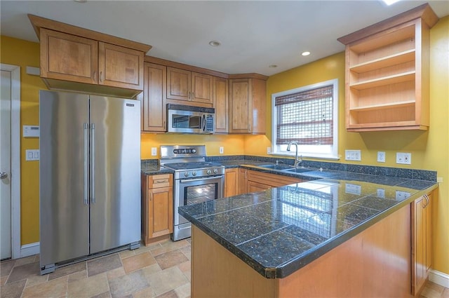 8811 W 66th Ter, Mission, KS 66202 - kitchen with stainless steel appliances, tile counters, a sink, brown cabinetry, and a peninsula