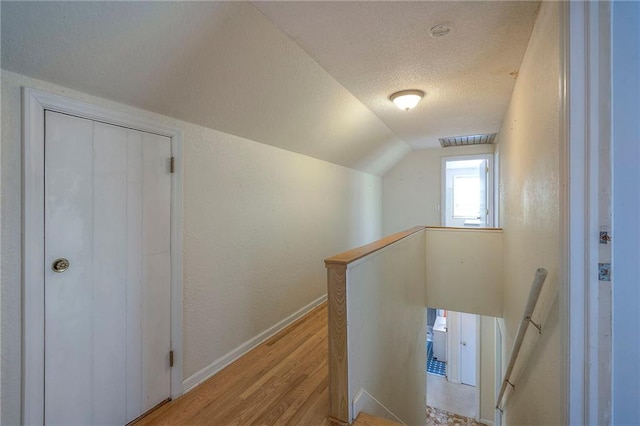 8811 W 66th Ter, Mission, KS 66202 - hall with an upstairs landing, light wood finished floors, baseboards, a textured ceiling, and vaulted ceiling