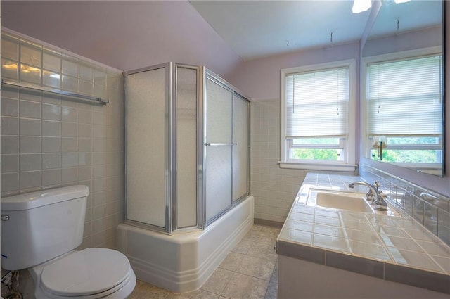8811 W 66th Ter, Mission, KS 66202 - full bathroom featuring tile walls, toilet, tile patterned flooring, bath / shower combo with glass door, and vanity