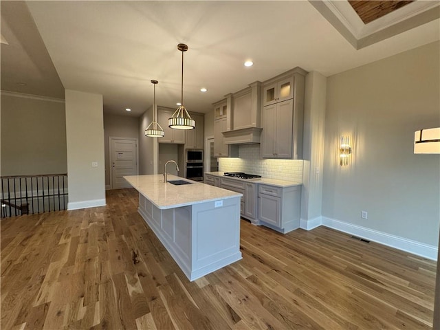 22428 W 90th Ter, Lenexa, KS 66227 - kitchen featuring baseboards, a sink, wood finished floors, backsplash, and an island with sink