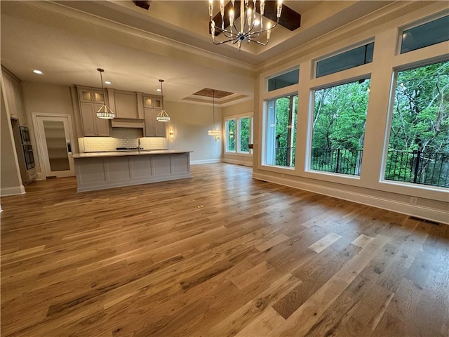 22428 W 90th Ter, Lenexa, KS 66227 - unfurnished living room featuring a chandelier, baseboards, a sink, light wood-type flooring, and ornamental molding