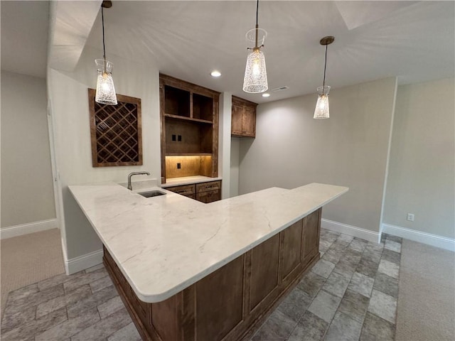 22428 W 90th Ter, Lenexa, KS 66227 - kitchen with a sink, baseboards, a peninsula, light stone counters, and hanging light fixtures