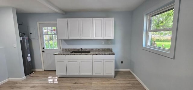 2918 S 52nd Ter, Kansas City, KS 66106 - kitchen featuring a sink, light wood finished floors, white cabinets, baseboards, and beamed ceiling