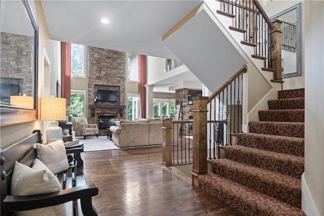 24901 W 91st Pl, Lenexa, KS 66227 - living area featuring a stone fireplace, wood finished floors, stairs, recessed lighting, and decorative columns