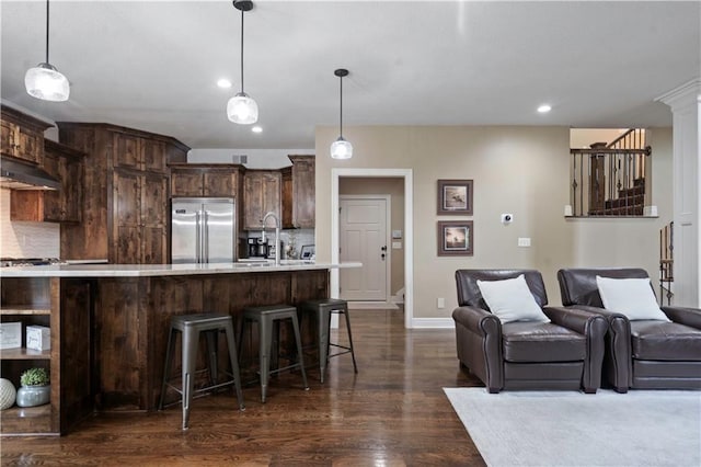 24901 W 91st Pl, Lenexa, KS 66227 - kitchen with built in refrigerator, light countertops, backsplash, dark brown cabinetry, and under cabinet range hood