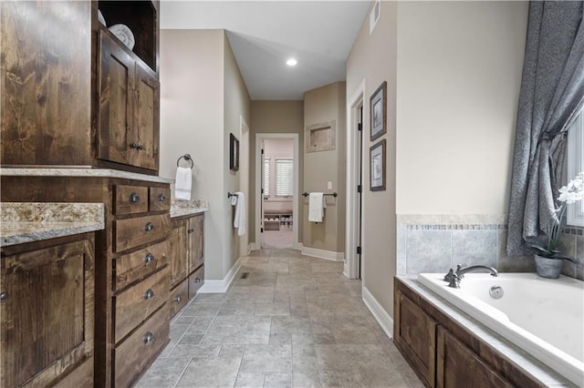 24901 W 91st Pl, Lenexa, KS 66227 - full bathroom featuring a garden tub, baseboards, stone finish floors, and vanity
