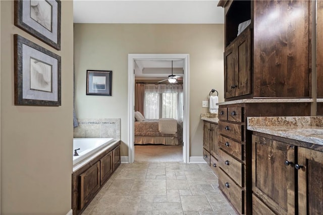 24901 W 91st Pl, Lenexa, KS 66227 - bathroom with ensuite bathroom, a bath, stone tile flooring, baseboards, and vanity