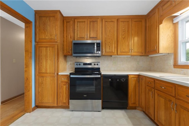 210 Murray Rd, Lees Summit, MO 64081 - kitchen with appliances with stainless steel finishes, brown cabinets, light countertops, and decorative backsplash