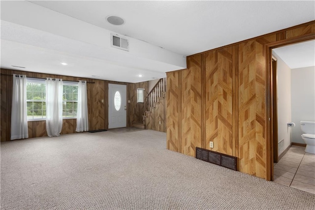210 Murray Rd, Lees Summit, MO 64081 - unfurnished living room featuring wooden walls, light carpet, and stairs