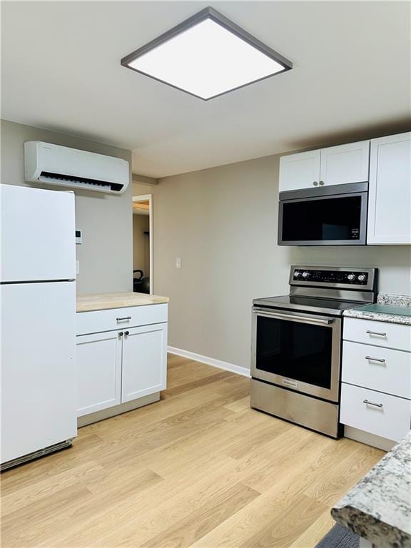 1700 Tilden St, Kansas City, MO 64126 - kitchen featuring stainless steel appliances, a wall mounted AC, light wood-type flooring, light countertops, and white cabinetry