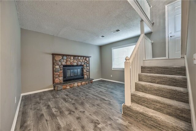 14033 Dornoch St, Grandview, MO 64030 - unfurnished living room with stairway, wood finished floors, baseboards, a textured ceiling, and a fireplace