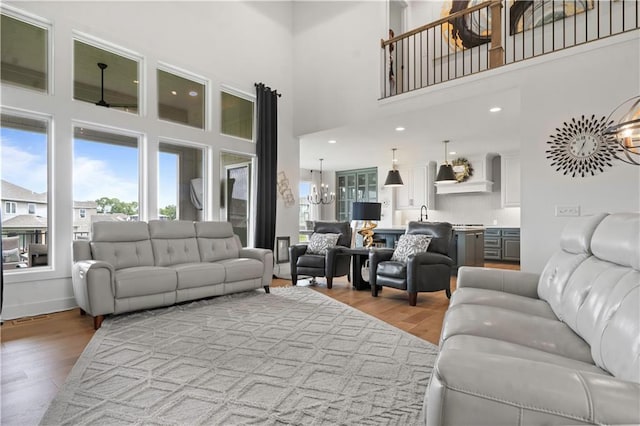 15318 W 172nd Pl, Olathe, KS 66062 - living room featuring healthy amount of natural light, a high ceiling, light wood-style flooring, and a chandelier