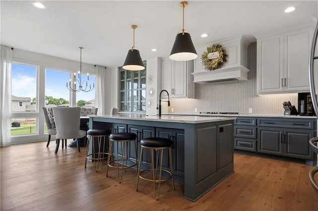 15318 W 172nd Pl, Olathe, KS 66062 - kitchen with gray cabinets, a center island with sink, light countertops, tasteful backsplash, and a chandelier