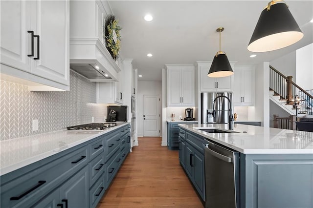 15318 W 172nd Pl, Olathe, KS 66062 - kitchen with appliances with stainless steel finishes, a sink, white cabinets, light wood-type flooring, and tasteful backsplash