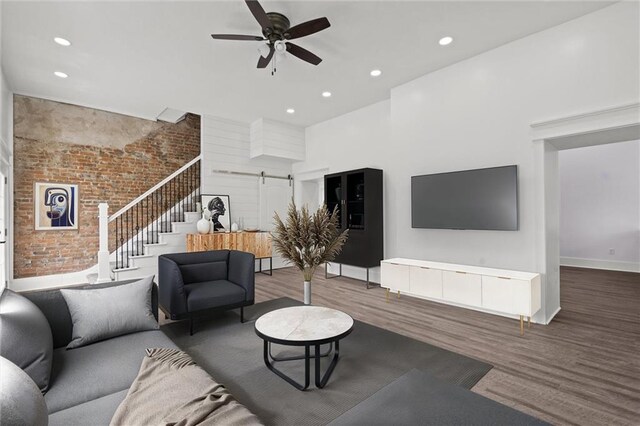 1003 Commercial St, Atchison, KS 66002 - living room featuring stairs, a barn door, wood finished floors, brick wall, and ceiling fan