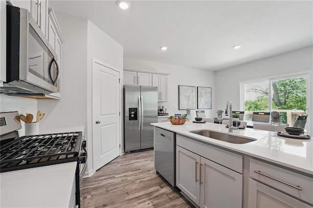 7708 NE 107th Ter, Kansas City, MO 64157 - kitchen featuring appliances with stainless steel finishes, a sink, light countertops, light wood-type flooring, and recessed lighting