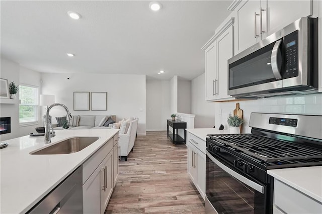 7708 NE 107th Ter, Kansas City, MO 64157 - kitchen featuring appliances with stainless steel finishes, a sink, light wood-style floors, light countertops, and open floor plan