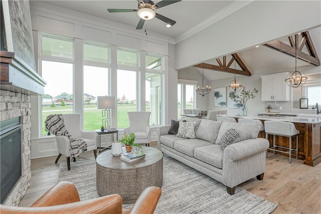 17162 S Hall St, Olathe, KS 66062 - living area featuring a chandelier, a stone fireplace, light wood-type flooring, plenty of natural light, and ornamental molding