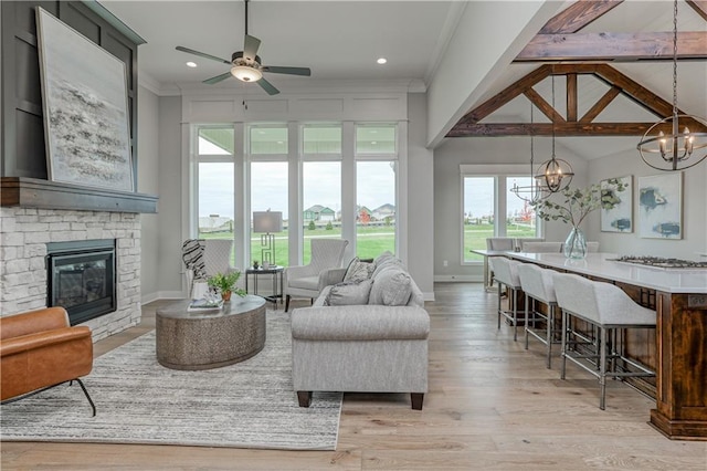 17162 S Hall St, Olathe, KS 66062 - living area featuring a chandelier, a stone fireplace, a ceiling fan, light wood-type flooring, and ornamental molding