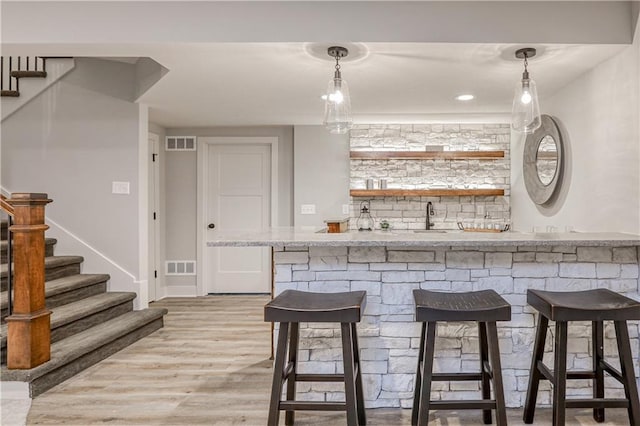 17162 S Hall St, Olathe, KS 66062 - indoor wet bar featuring stairs, light wood finished floors, and hanging light fixtures