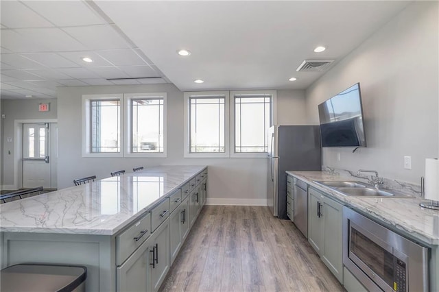 17162 S Hall St, Olathe, KS 66062 - kitchen featuring stainless steel appliances, a sink, a peninsula, light wood-style floors, and light stone countertops