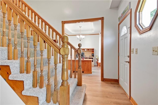 8215 W 150th St, Overland Park, KS 66223 - entryway with a chandelier, baseboards, a raised ceiling, stairs, and light wood-style flooring