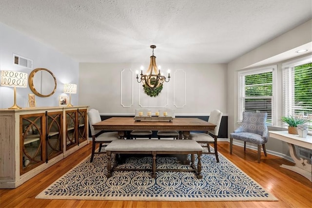 607 E 110th St, Kansas City, MO 64131 - dining room with wood finished floors, a chandelier, a textured ceiling, and baseboards