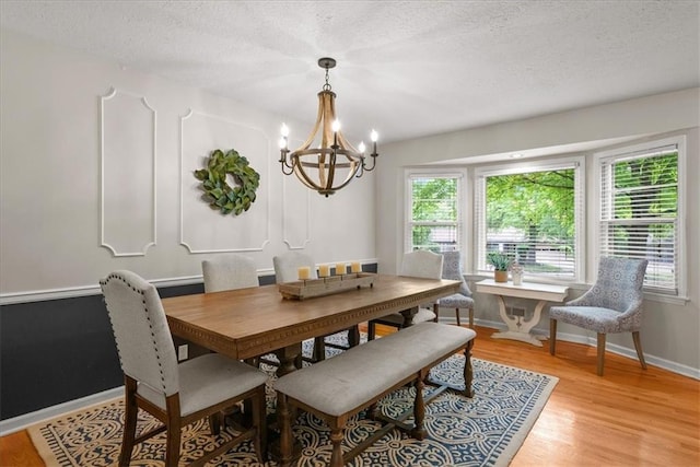 607 E 110th St, Kansas City, MO 64131 - dining area with a chandelier, a textured ceiling, plenty of natural light, light wood finished floors, and baseboards