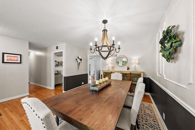 607 E 110th St, Kansas City, MO 64131 - dining space featuring a chandelier, light wood-type flooring, baseboards, and a textured ceiling