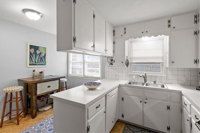 607 E 110th St, Kansas City, MO 64131 - kitchen with white dishwasher, a sink, a peninsula, decorative backsplash, and light countertops