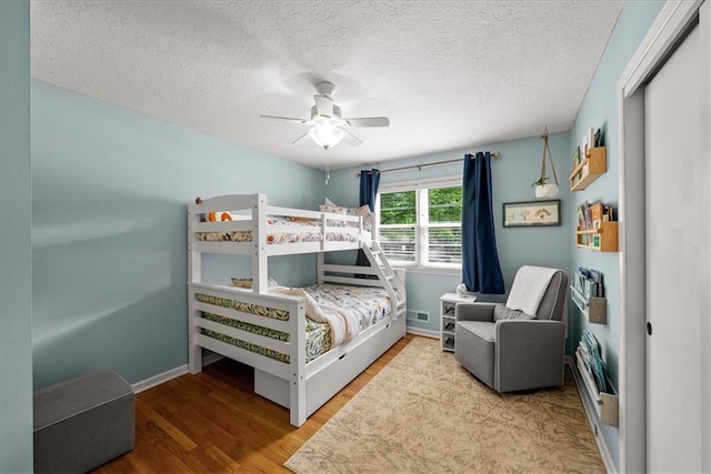607 E 110th St, Kansas City, MO 64131 - bedroom featuring wood finished floors, baseboards, a textured ceiling, a closet, and ceiling fan