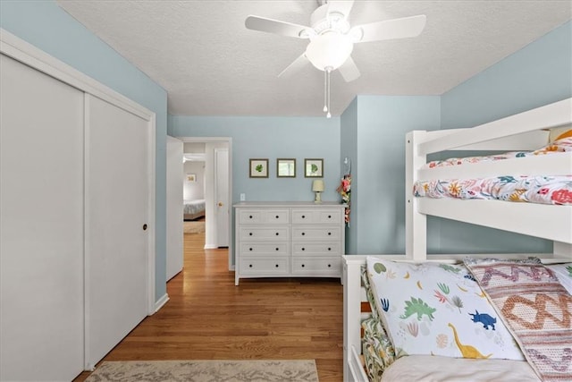 607 E 110th St, Kansas City, MO 64131 - bedroom with wood finished floors, a textured ceiling, a closet, and a ceiling fan