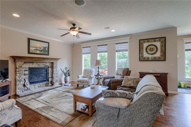 25005 W 85th Ter, Lenexa, KS 66227 - living area with crown molding, hardwood / wood-style flooring, a stone fireplace, a textured ceiling, and ceiling fan