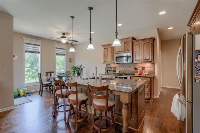 25005 W 85th Ter, Lenexa, KS 66227 - kitchen featuring stainless steel appliances, brown cabinets, a ceiling fan, decorative backsplash, and dark wood-type flooring