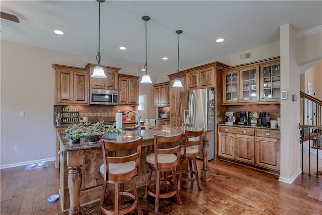 25005 W 85th Ter, Lenexa, KS 66227 - kitchen featuring appliances with stainless steel finishes, brown cabinetry, a breakfast bar, backsplash, and dark wood-type flooring