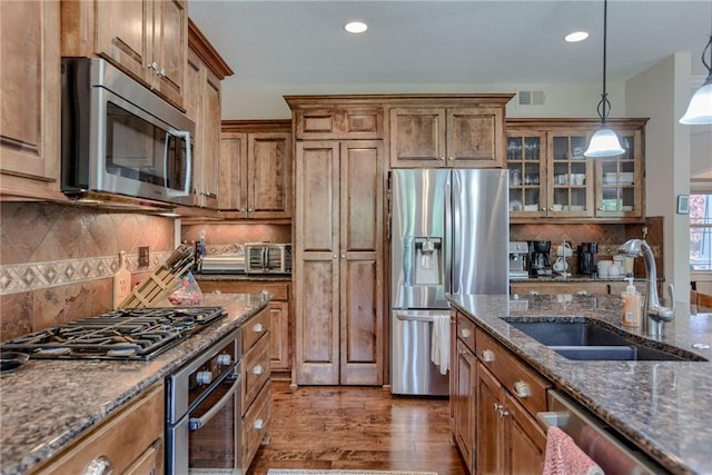25005 W 85th Ter, Lenexa, KS 66227 - kitchen with appliances with stainless steel finishes, brown cabinetry, wood finished floors, decorative light fixtures, and glass insert cabinets