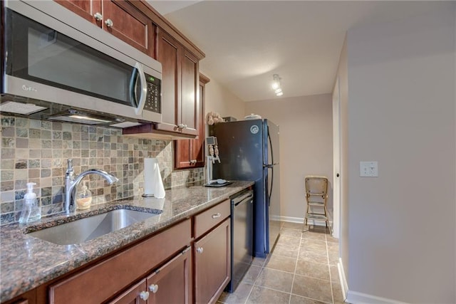 25005 W 85th Ter, Lenexa, KS 66227 - kitchen with stainless steel appliances, decorative backsplash, dark stone countertops, light tile patterned flooring, and brown cabinetry