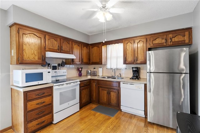 215 SE Country Ln, Lees Summit, MO 64063 - kitchen with white appliances, a sink, under cabinet range hood, tasteful backsplash, and light countertops